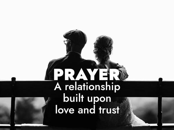 A black and white photo of a couple sitting on a bench with the words Prayer - A relationship built upon love and trust